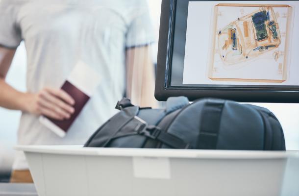 Airport security check. Young man holding passport and waiting for x-ray control his luggage.